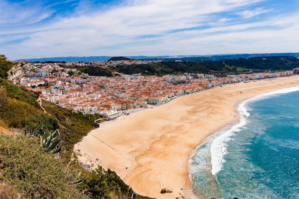Underbar romantisk eftermiddag panoramautsikt över kusten i Atlanten. Se Nazare strandrivier, Praia da Nazare, med stadsbilden av Nazare stad under lågsäsong vid soligt väder. Portugal.