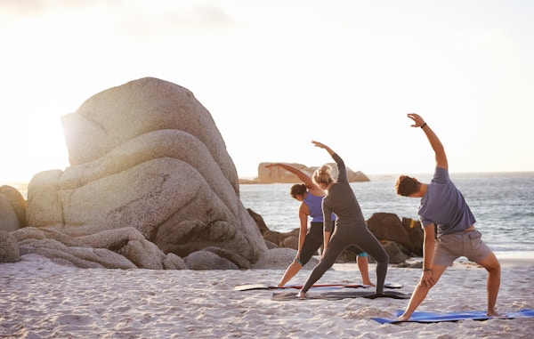 Skott av en grupp människor som övar yoga på stranden