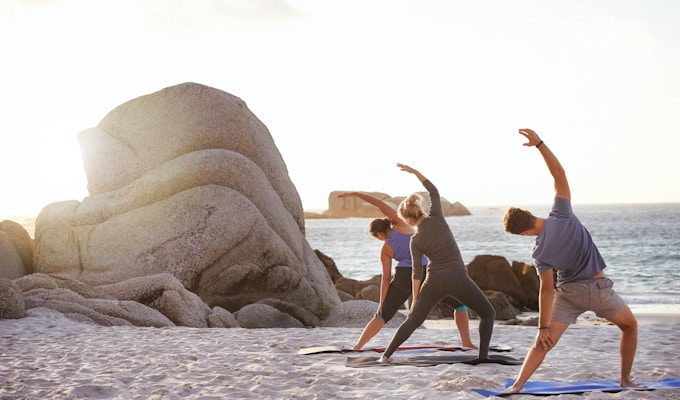 Skott av en grupp människor som övar yoga på stranden