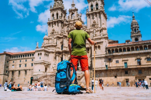 Ung backpackerpilgrim som står på Obradeiro-torget (torget) - huvudtorget i Santiago de Compostela.
