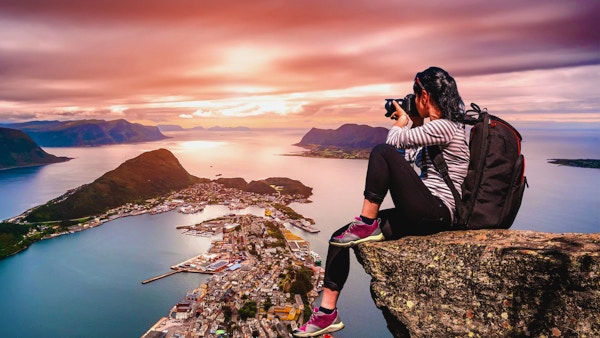 Naturfotograf turist med kameran skjuter medan du står på toppen av berget. Aksla i staden Ålesund, Norge.