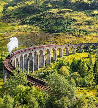 Glenfinnan Railway Viaduct i Skottland med ångtåg passerar.