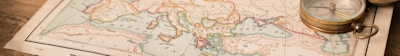 "Färgbild av en gammal karta över Europa, från 1800-talet, med kikare och kompass, på träbakgrund. Karta är från en gammal geografibok med 1870 upphovsrätt."