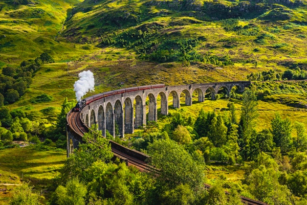 Glenfinnan Railway Viaduct i Skottland med ångtåg passerar.