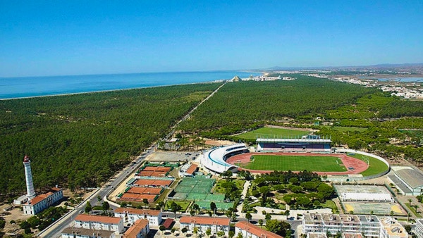 Sportcentret från ovan med kusten och hotellen på stranden i bakgrunden, blå himmel, Atlanten, Monte Gordo, Portugal