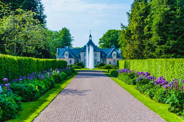 Vacker grusgång omgiven av häckar och blommoar, gångnen leder fram till en sprutande fontän framför Villa Albelin, Norrvikens Trädgårdar, Bjärehalvön, Skåne, Sverige