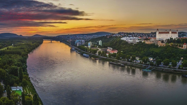 Slott av Bratislava på den högra stranden av Donau River vid solnedgången
