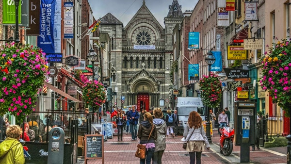 Grafton Streets berömda shoppingområde, blommor, shoppare, affärer och kyrka, Dublin, Irland