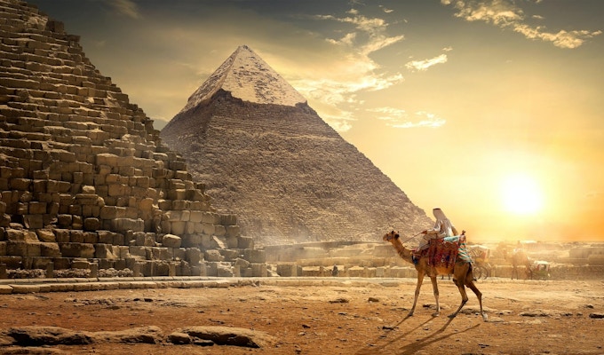 Nomad på kamel nära pyramider i den egyptiska öknen