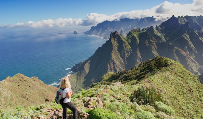 Kvinnafotvandrare som håller ögonen på härligt costal landskap. - Teneriffa, Kanarieöarna, Spanien. Västra kustvy, berg Anaga och Atlanten