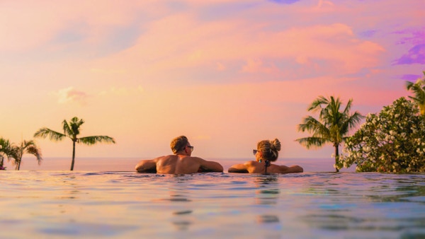 Romantic couple looking at beautiful sunset in luxury infinity pool