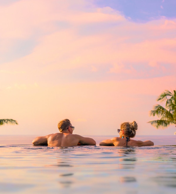 Romantic couple looking at beautiful sunset in luxury infinity pool