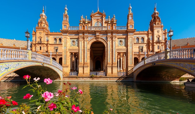 Spain Square eller Plaza de España i Sevilla på den solfylte sommerdagen, Andalusia, Spania. Blomsterbed, broer og kanal i forgrunnen