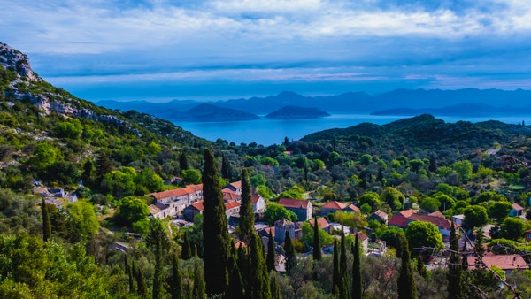 Mljet Island, Kroatien - 4 maj 2015 - Liten by på ön Mljet, Kroatien, med Adriatiska havet och bergen i bakgrunden.