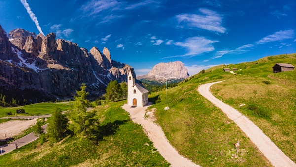 Vacker flygvy till stigen till det lilla San Maurizio-kapellet och Dolomiti bergslandskap i bakgrunden, en sadel mellan Sella-massivet i söder och Cirspitzen i norr. Gardena Pass, Val Gardena, Groeden, Bolzano, Trentino Alto Adige, Italien