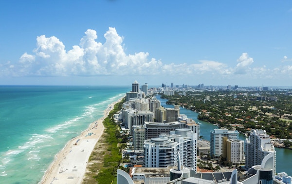 Ser ner South Beach i Miami. Full utsikt över stranden till vänster och staden till höger. Härlig blå himmel på en klar dag.