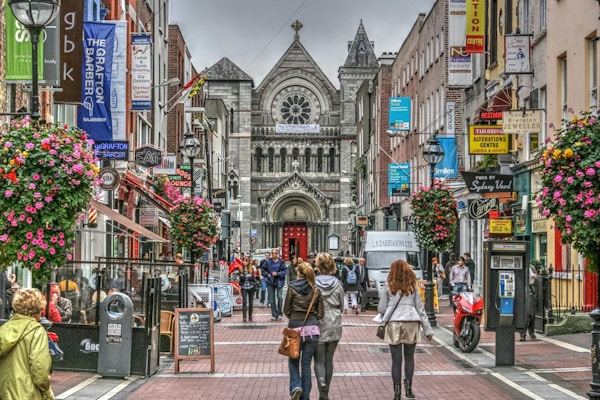 Grafton Streets berömda shoppingområde, blommor, shoppare, affärer och kyrka, Dublin, Irland