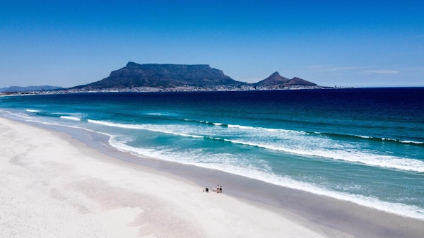Vacker sandstrand en solig dag, underbar utsikt mot Kapstaden och Taffelberget, Sydafrika