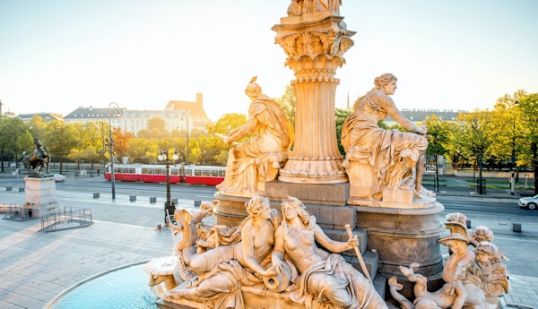 Athena staty nära Parlament byggnad med Wien stadsbild och gammal spårvagn på bakgrunden vid soluppgången