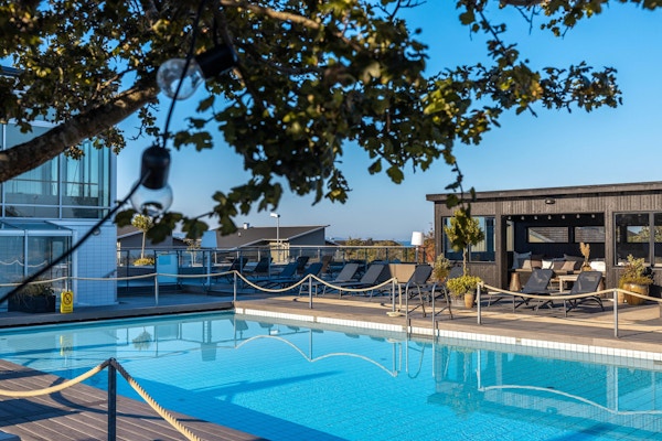 Utomhuspool med trädäck, séparée, lounge, solstolar, blå himmel och sol, Torekov Hotell, Båstad, Sverige