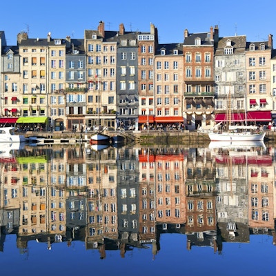 Honfleur hamn i Normandie, Frankrike. Färghus och deras reflektion i vatten.