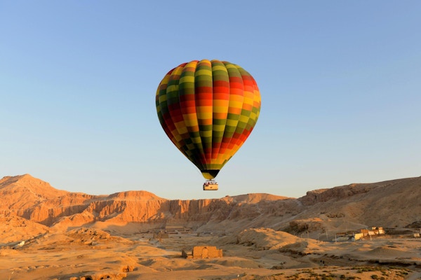 Luftballong som lyfter av i luxor Egypten med templet för hatshepsut i bakgrund