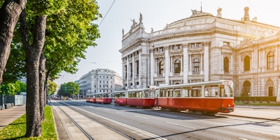 Famous Wiener Ringstrasse with historic Burgtheater (Imperial Court Theatre) and traditional red electric tram at sunrise with retro vintage Instagram style filter effect in Vienna, Austria.