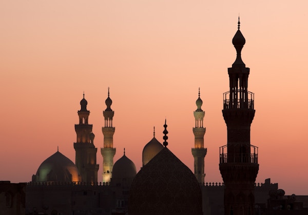 Minareter och kupoler mot en rosa himmel med solnedgång.