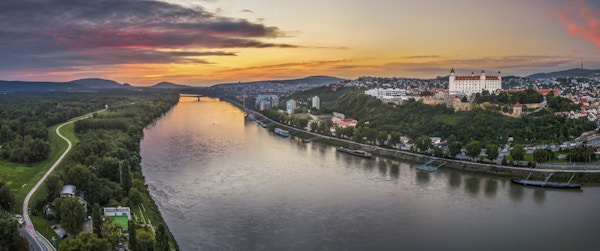 Slott av Bratislava på den högra stranden av Donau River vid solnedgången