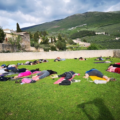 Grupp människor som ligger på magen och kopplar av efter en yogasession på landsbygden.