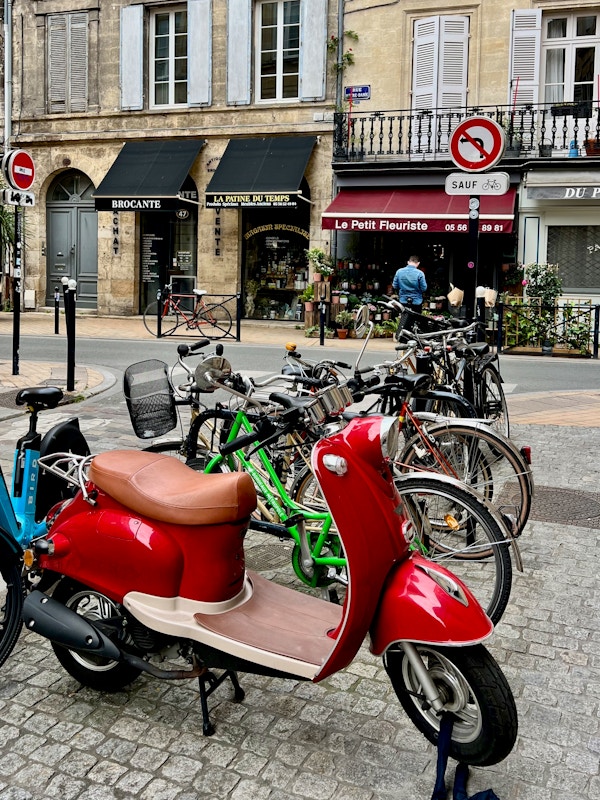En röd vespa och cyklar i Bordeaux
