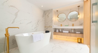 Badrum med fristående badkar och guldig fristående kran, vit marmor, spelglar, L'Azure Hotel, Lloret de Mar, Spanien