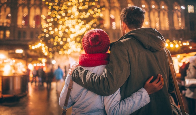 Fotoet av ett ungt par tycker om dekorationen på julmarknaden, under julferier