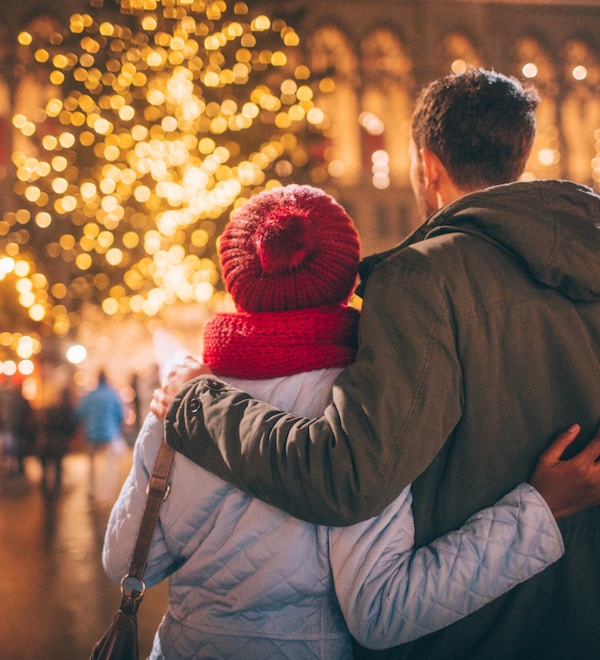 Fotoet av ett ungt par tycker om dekorationen på julmarknaden, under julferier