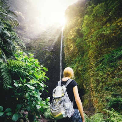 Ung kvinna som tycker om vattenfallet Caldeiré Verde när hon vandrar på Madeira Island.