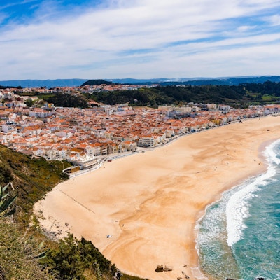 Underbar romantisk eftermiddag panoramautsikt över kusten i Atlanten. Se Nazare strandrivier, Praia da Nazare, med stadsbilden av Nazare stad under lågsäsong vid soligt väder. Portugal.