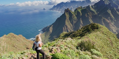 Kvinnafotvandrare som håller ögonen på härligt costal landskap. - Teneriffa, Kanarieöarna, Spanien. Västra kustvy, berg Anaga och Atlanten