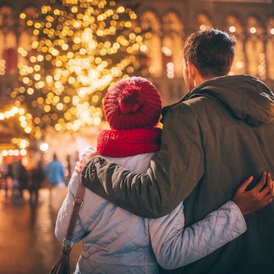 Fotoet av ett ungt par tycker om dekorationen på julmarknaden, under julferier